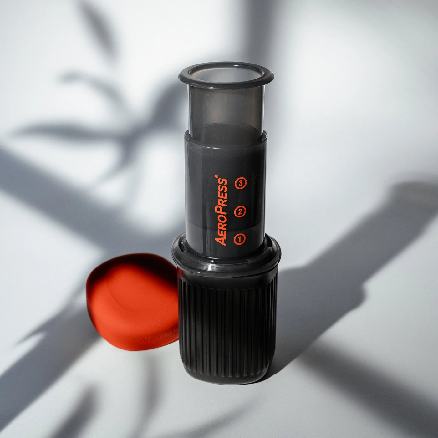 AeroPress Go coffee maker on a white surface with a red lid.